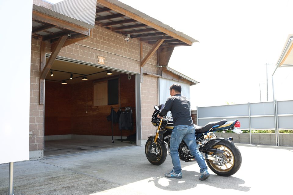 シャッターを開けたガレージにバイクを押して入れるところ